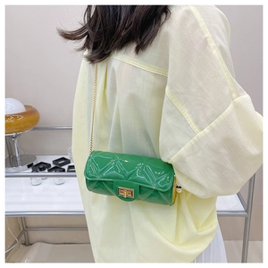 Close-up of green quilted cylindrical mini bag with golden chain and pearl detail