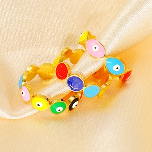 Macro detail of gold-plated evil eye and smiley rings on champagne silk fabric