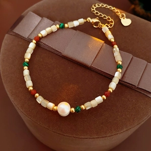 Détail d'un bracelet en perles avec accents dorés et pierres de malachite sur velours