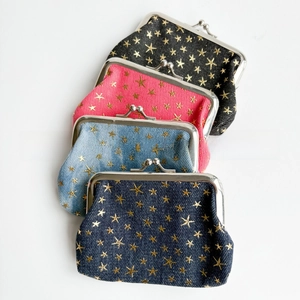 Detailed view of 4-color denim kiss-lock pouches with gold star patterns and vintage metal clips