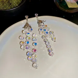 Orecchini a nappa con zirconi scintillanti e perle di cristallo su vassoio in ceramica