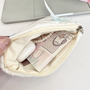 Internal view of a white quilted cosmetic bag with blue zipper and bow detail