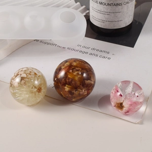 Detailed view of spherical silicone mold with resin pendants containing dried flowers