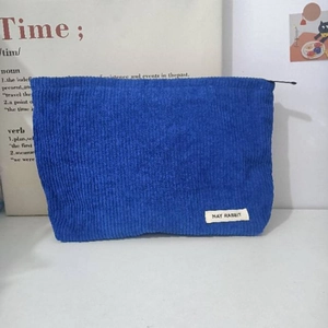 Close-up of blue corduroy cosmetic bag featuring a vintage ribbed texture and white label
