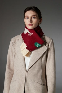 Detail of red Christmas scarf with deer pattern and off-white ribbed knit edges on beige coat
