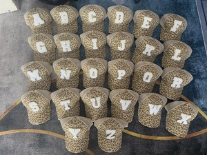 Detailed collection of leopard print trucker hats featuring large glitter-edged alphabet patches