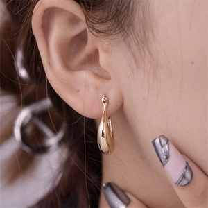 Close-up of polished gold teardrop hoop earrings worn by a model for a luxury daily look