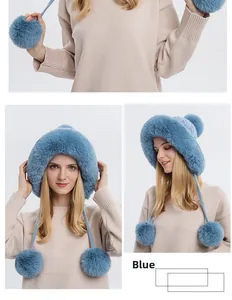 Close-up of blue winter knit hat featuring plush faux fur lining and large dual pom-poms