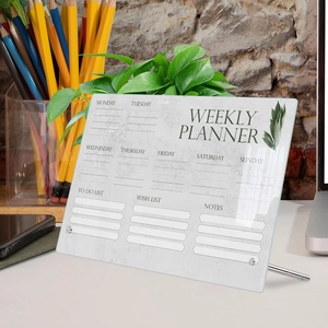 Macro shot of clear acrylic weekly planner board with metal stand and organizer layout