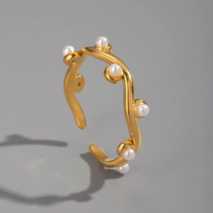 Close-up of a gold-plated wavy cuff bracelet adorned with delicate small pearls