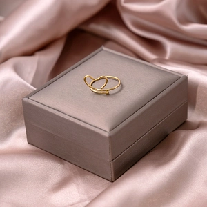 Elegant gold heart ring displayed on a velvet jewelry box with silk background texture