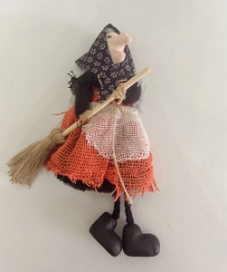 Detail of handmade Halloween witch doll with orange burlap skirt and wooden broom decoration