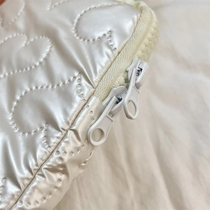 Detail view of smooth double zipper closure on white heart quilted laptop sleeve case