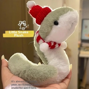 Detail of a green plush snake toy wearing a red knitted hat and a striped scarf