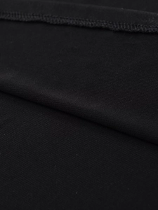 Macro shot of black crepe fabric with fine knit texture and neat stitching details