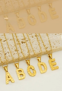 Close-up of 18K gold plated stainless steel letter pendants with unique cracked texture
