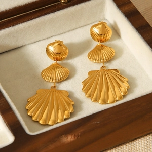 Close-up of 18K gold-plated stainless steel shell earrings in a velvet wooden jewelry box