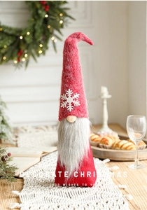 Close-up of a plush red Christmas gnome decoration with a white snowflake on its tall hat