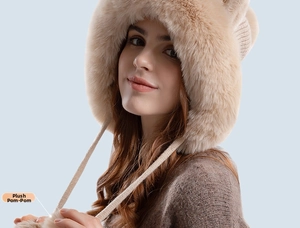 Detail of soft faux fur ear flaps and plush pom-pom ties on a winter knit beanie