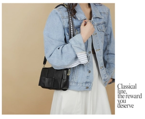 Detail view of a black woven leather crossbody bag styled with a casual denim outfit