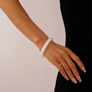 Close-up of a white translucent acrylic resin bangle worn on wrist with black attire