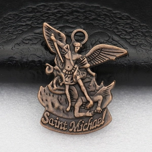 Detailed close-up of antique bronze Saint Michael metal pendant on textured surface