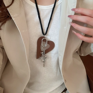 Detail of leather heart and silver puppy charm necklace on woven cord over a blazer