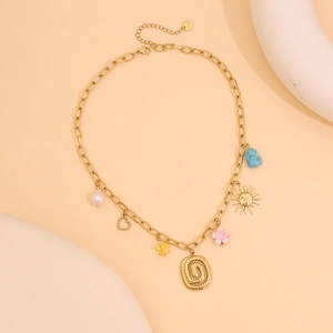 Détail macro du collier en acier inoxydable doré avec breloques cœur et papillon
