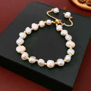 Macro shot of adjustable imitation pearl bracelet with gold beads on black box