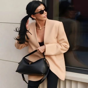 Detail of loose beige blazer paired with a black faux leather croissant shoulder bag