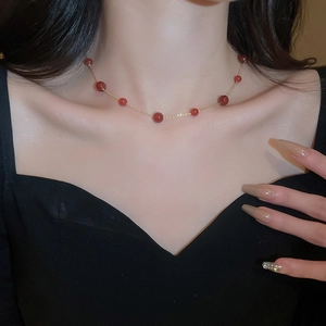 Close-up of elegant red beaded necklace with gold chain worn on the collarbone