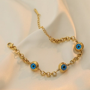 Golden chain bracelet with blue evil eye pendants on a silk background for women
