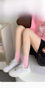 Detailed texture of pink ribbed mid-calf cotton socks styled with white sneakers