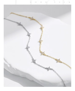 Detail shot of gold and silver four-leaf clover bracelets with sparkling zircons on stone