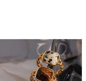 Macro shot of gold-finished rope bands featuring marble and tiger eye stone settings