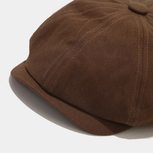 Close-up of brown newsboy cap showing textured heavy twill fabric and premium stitching