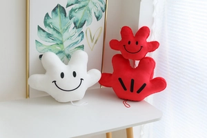 Detail of plush cartoon palm pillows with classic white and red glove designs on a table