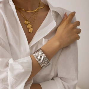 Detail showing high-polish silver cuff bracelet with irregular hammered metal texture