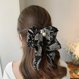 Elegant black bow hair clip with white paisley pattern and faux pearl embellishments