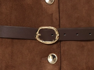 Gros plan sur la texture d'une veste en daim marron avec boucle en métal doré