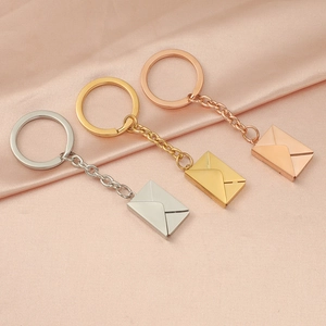 Detailed view of polished envelope charms in silver, gold, and rose gold on pink silk
