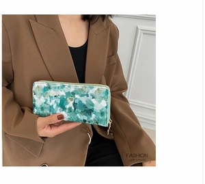 Detail of green watercolor marble long wallet with gold zipper held by a female model