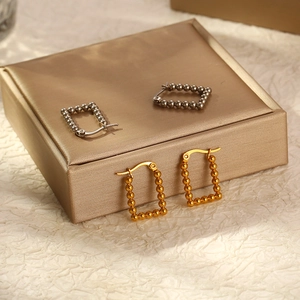 Rectangular beaded hoop earrings in gold and silver finish on a luxury jewelry box