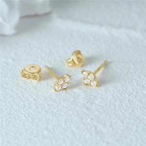 Macro shot of gold silver stud earrings with four-diamond floral square pattern