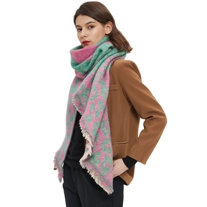 Pink and green plaid scarf with fringe tassels worn over a brown blazer on white background