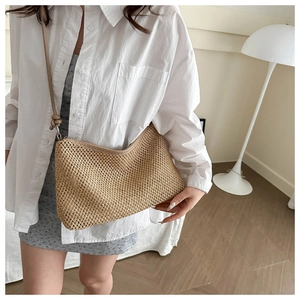 Detail of beige woven straw tote bag with smooth leather strap and sleek zipper closure