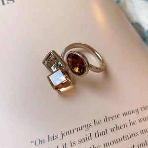 Macro shot of silver ring with amber and clear geometric crystals on a magazine page