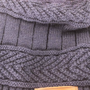 Macro detail of dark blue knit fabric with ribbed and braided texture on winter beanie