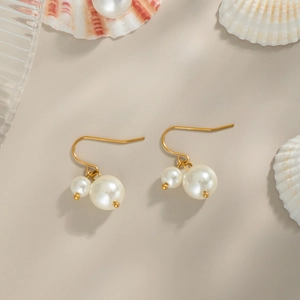 Boucles d'oreilles perles vintage dorées sur fond décoratif de bord de mer chic