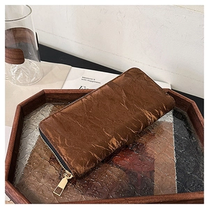 Brown long wallet with pleated vintage texture in a wooden tray lifestyle setting